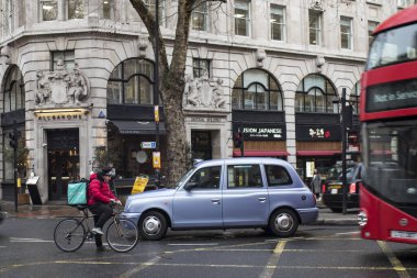 Londra, Uk - 13 Şubat 2020, gri bir binanın arka planında kırmızı otobüs ve siyah taksi.