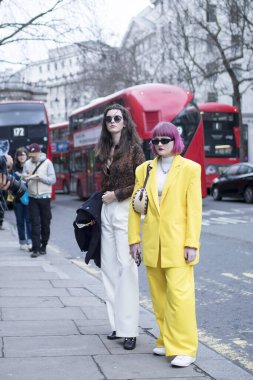 LONDON, UK- febryary 15 2020: Fashionable people on the street . Street style. Girl in a yellow pantsuit and pink hair in sunglasses.