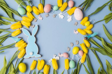 Sarı lale buketi, paskalya tavşanı ve mavi arka planda yumurtalar. Uzayı kopyala Tasarımcı kartı.
