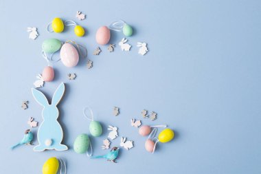 Mavi arka planda plastik yumurta ve kartla mavi tahta düz paskalya tavşanı. Boşluğu kopyala