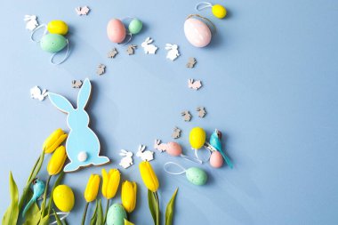 Sarı lale buketi, paskalya tavşanı ve mavi arka planda yumurtalar. Uzayı kopyala Tasarımcı kartı.