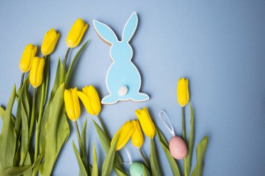 Sarı lale buketi, paskalya tavşanı ve mavi arka planda yumurtalar. Uzayı kopyala Tasarımcı kartı.