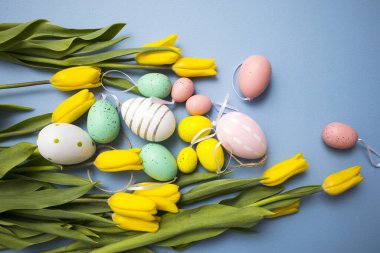 Sarı lale buketi, paskalya tavşanı ve mavi arka planda yumurtalar. Uzayı kopyala Tasarımcı kartı.