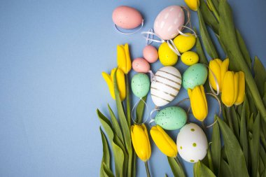 Sarı lale buketi, paskalya tavşanı ve mavi arka planda yumurtalar. Uzayı kopyala Tasarımcı kartı.