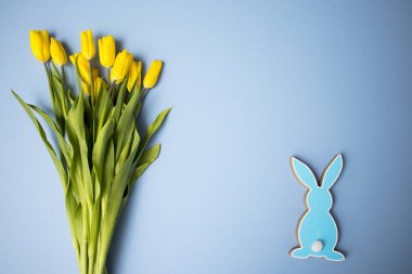 Sarı lale buketi, paskalya tavşanı ve mavi arka planda yumurtalar. Uzayı kopyala Tasarımcı kartı.