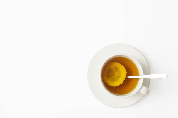 白いテーブルの上にソーサーとスプーンでレモンとお茶の白いカップ 正方形のフレーム スペースのコピー — ストック写真