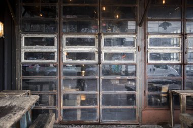LONDON, İngiltere - 20 Mart 2020: Hipster cafe, zeminde camları olan, eski bir fabrikaya benzeyen kötü hava koşullarında masaları olan