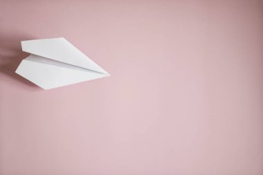 Düz beyaz kağıt uçak pembe arka planda yatıyordu. Boşluğu kopyala.