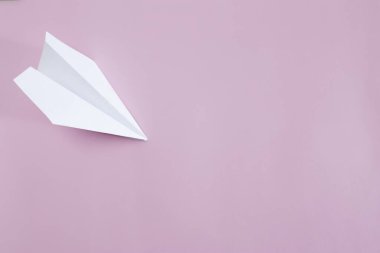 Düz beyaz kağıt uçak pembe arka planda yatıyordu. Boşluğu kopyala.