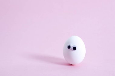 Yalnız yumurta, pembe bir arka planda yalnızlığın bir sembolü olarak gözler. Boşluğu kopyala