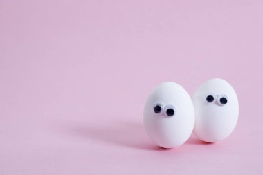 konsept sosyal ağlar iletişim ve duygular - pembe arka planda yumurtalar göz kırpıyor. Boşluğu kopyala