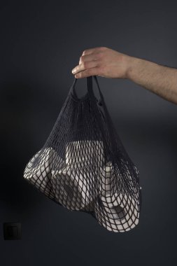 Adamın eli tuvalet kağıdı rulolarının olduğu bir torba tutuyor. Hijyen konsepti..