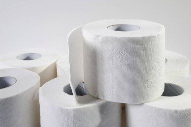 Gri arka planda beyaz tuvalet kağıdı yuvarlanıyor. Hijyen kavramı.