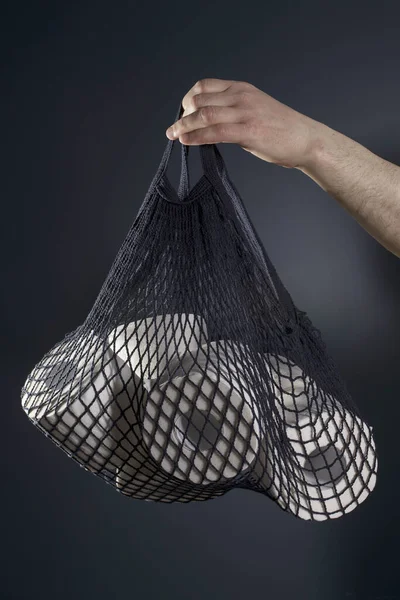 Adamın eli tuvalet kağıdı rulolarının olduğu bir torba tutuyor. Hijyen konsepti..