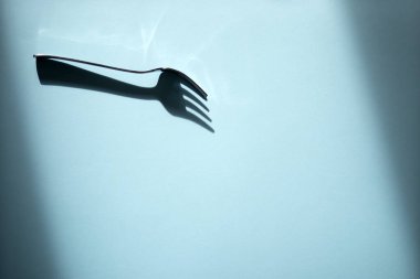 Mavi kağıtta koyu gölgesi olan demir çatal. Boşluğu kopyala