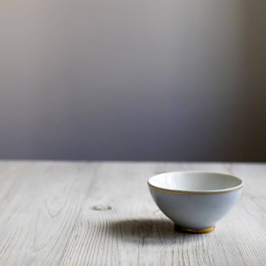 Mutfaktaki masanın ahşap yüzeyinde altın kenarlı küçük mavi kase. Boşluğu kopyala