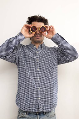 Ekose gömlekli komik kıvırcık adam gözlerine kırmızı turuncu bir portakal parçası koydu. Komik resim.