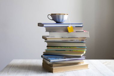 Üstünde poşet olan çay fincanı olan bir yığın kitap. Coronovirus Çevrimiçi Öğrenme