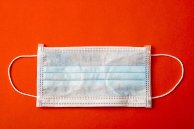 Kırmızı arka planda basit bir tıbbi maske. Yaratıcı. Boşluğu kopyala.