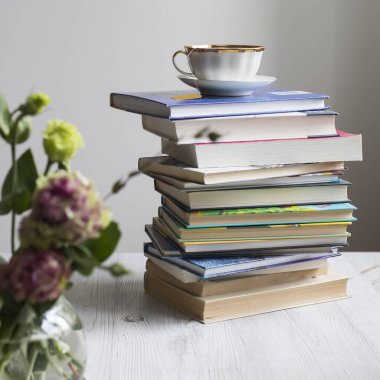Üstünde poşet olan çay fincanı olan bir yığın kitap. Coronovirus Çevrimiçi Öğrenme