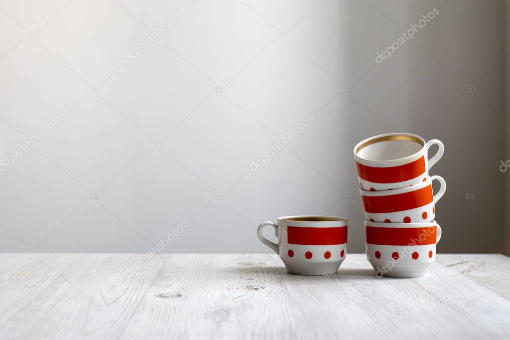 Red vintage striped and dot mugs of different shapes on a wooden table in the kitchen. Copy space