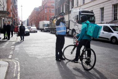 Londra, İngiltere - 15 Ocak 2020, Bir polis memuru bisikletli bir kuryeyi durdurdu ve belgeleri kontrol etti