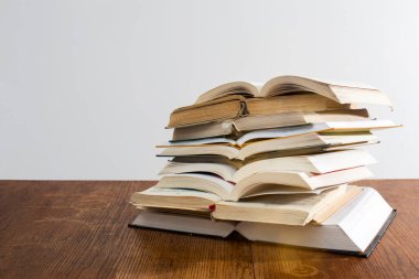 Üniversite sınavlarına hazırlanmak için beyaz arka plandaki tahta bir masada bir sürü eğitici açık kitap. Kendi kendini eğitme. Tecrit zamanında çevrimiçi eğitim