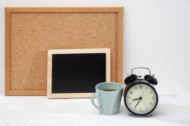 Duvarın yanındaki beyaz bir masada yazılı yazı için arka planda bir kupa çay ve bir çalar saat var. Metin için boş boşluk.