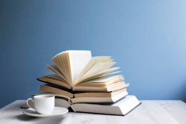 Mavi bir duvarın arkasında açık bir kitap ve bir fincan kahve. Kavram - çevrimiçi öğrenme. Uzayı kopyala Eğitim çevrimiçi
