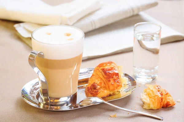 Cup of latte with croissant. Tablecloth background with newspape — Stockfoto