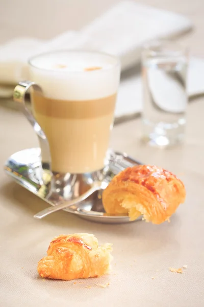 Cup of latte with croissant. Tablecloth background with newspape — Stockfoto