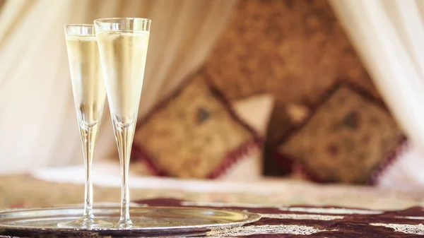 Dos copas de champán con cama de dosel oriental en el fondo —  Fotos de Stock