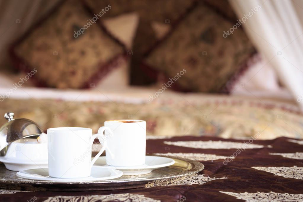 Two turkish coffee cups with oriental canopy bed at the backgrou