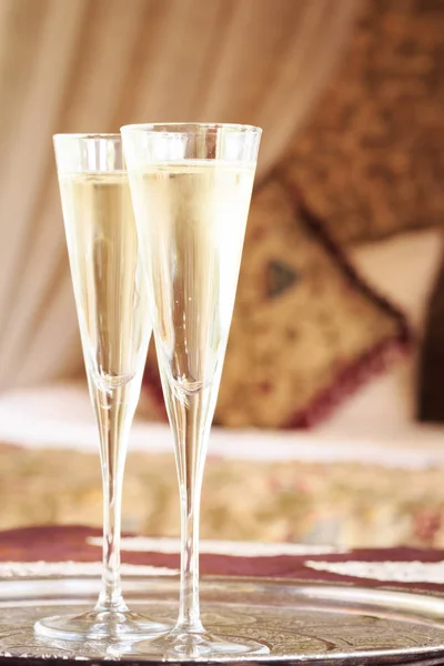 Dos copas de champán con cama de dosel oriental en el fondo — Foto de Stock