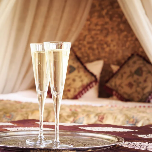 Dos copas de champán con cama de dosel oriental en el fondo — Foto de Stock