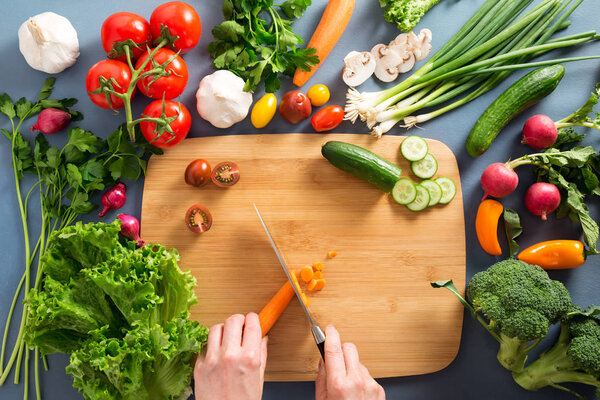 Top view of woman cooking healthy food: cutting vegetable ingred