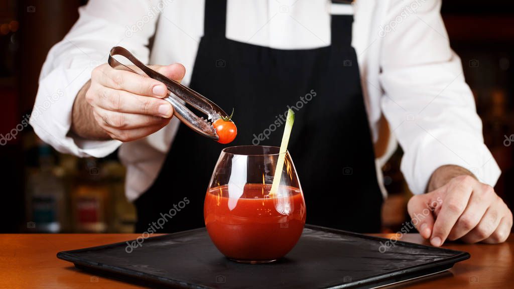 Bartender decorating Bloody Mary or Ceasar cocktail at the bar c