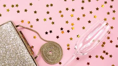 Festival akşam altın debriyaj ve şampanya kadehi ile pembe üzerinde parlayan yıldız sprinkles. Tatil ve kutlama arka plan. Lüks aksesuarları ve parti konsept