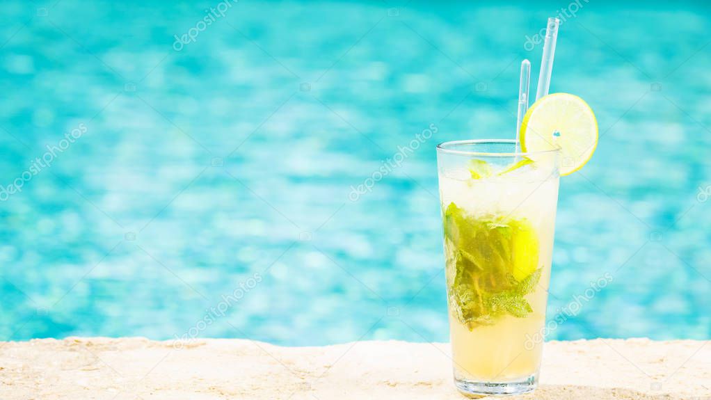 Mojito cocktail at the edge of a resort pool.  Concept of luxury