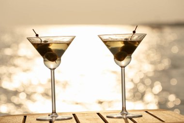 İki martini kokteyl batımında ahşap iskelede. Lüks resor