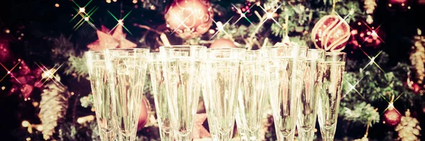 Glasses of champagne with Christmas tree background and sparkles