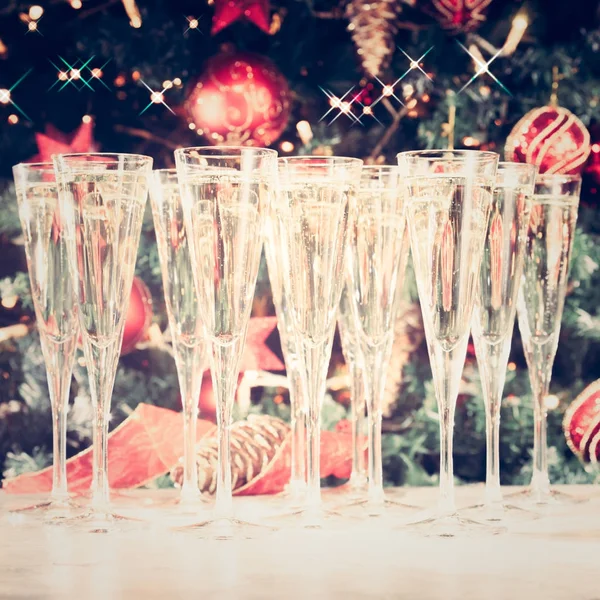 Glasses of champagne with Christmas tree background and sparkles