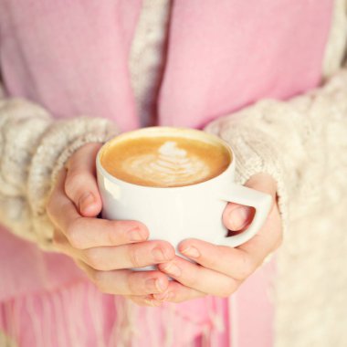 Bir fincan kahve ya da sıcak çikolata ya da chai çay latte tutan kız.