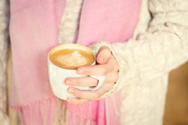 Bir fincan kahve ya da sıcak çikolata ya da chai çay latte tutan kız.