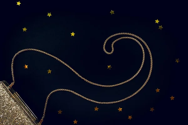 Festive evening golden clutch with star sprinkles on black. Holi