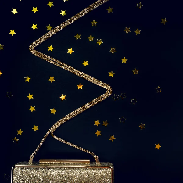 Festive evening golden clutch with star sprinkles on black. Holi