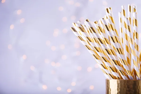 Gold und weißes Papier Strohhalme im goldenen Glas. Weihnachtsbeleuchtung — Stockfoto