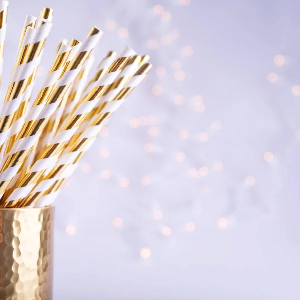 Gold and white paper straws in the golden glass. Christmas conce