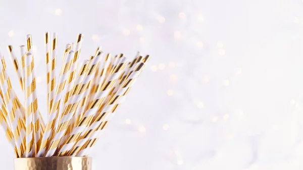 Gold and white paper straws in the golden glass. Christmas conce