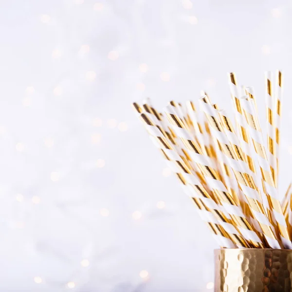 Gold and white paper straws in the golden glass. Christmas conce